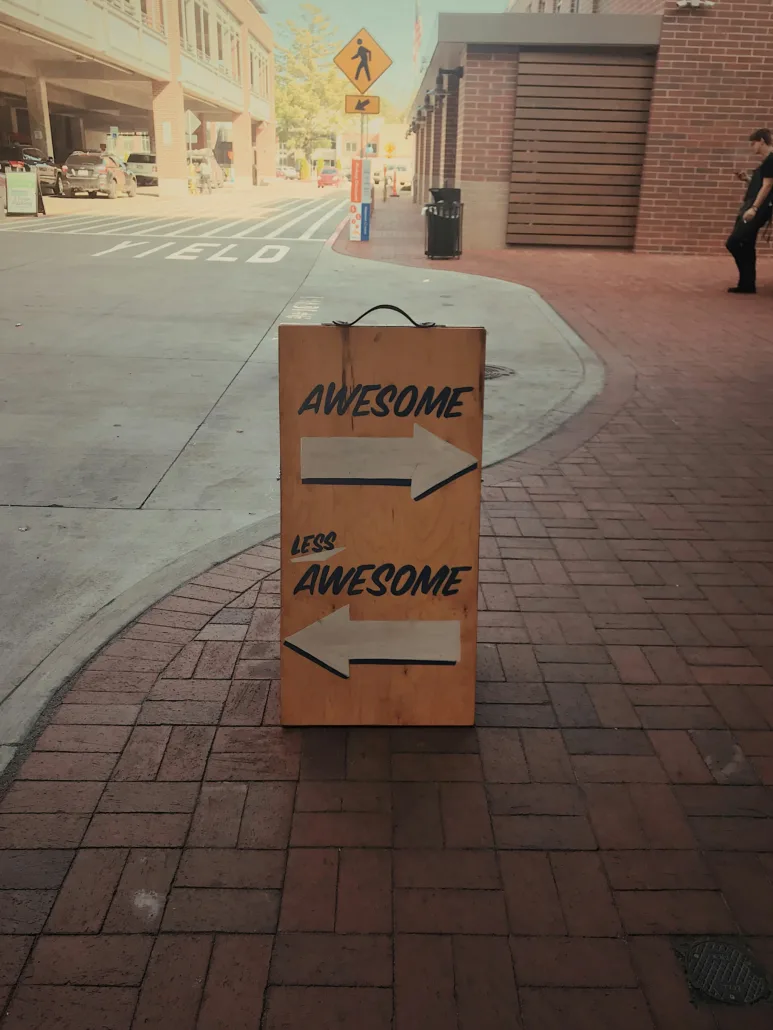 A sign that says "Awesome" with an arrow in one direction and "Less Awesome" in another direction. Symbolic of customer survey (kundundersökning) feedback giving you "direction".